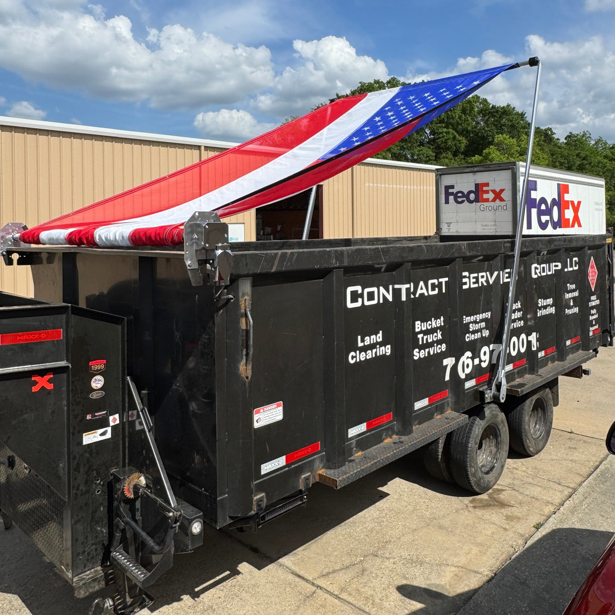 Customer's MAXX-D dump trailer with a Patriot Aluminum Electric Tarping System and 8' x 24' Mesh American Flag Tarp installed on it.
