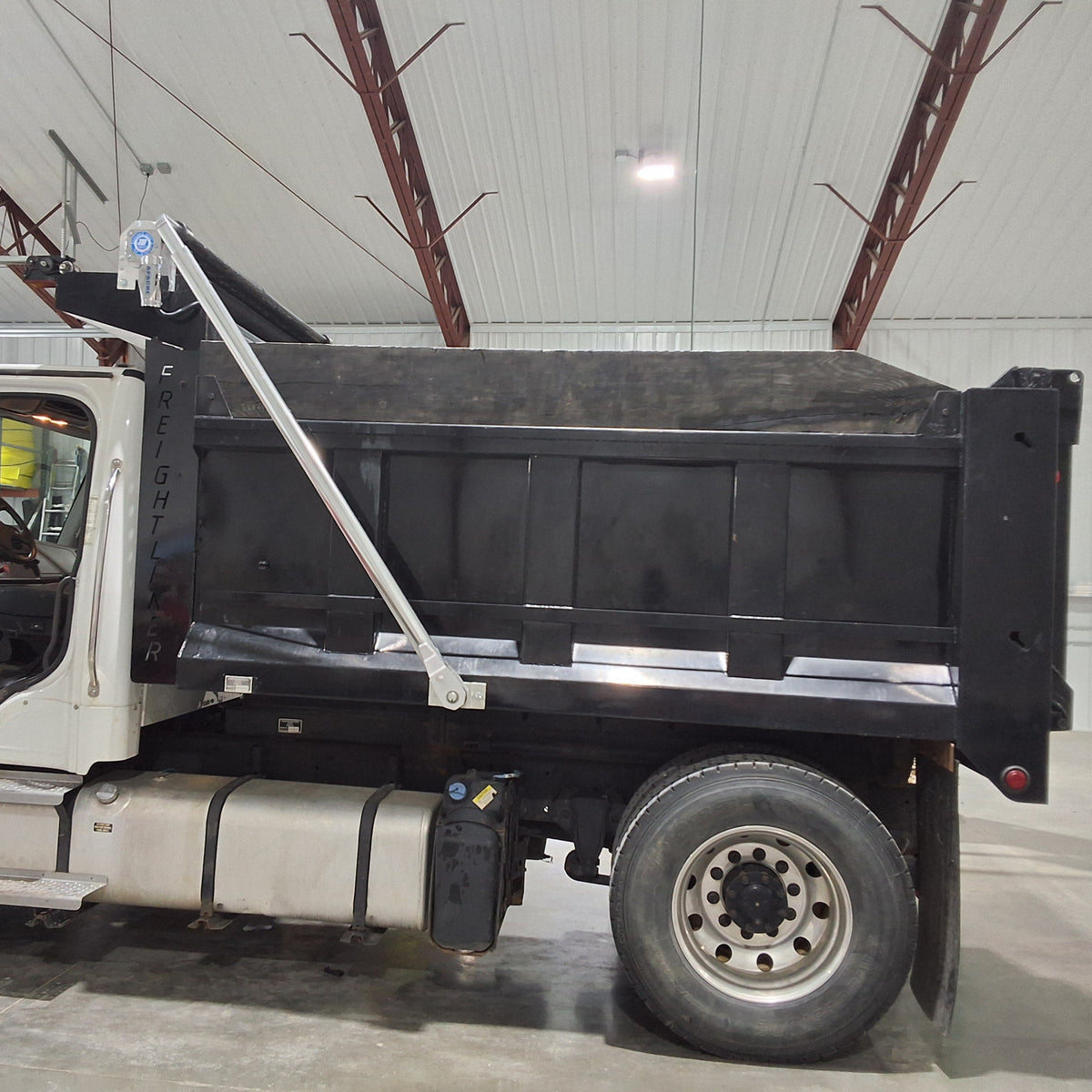 Dealer's customer's freightliner dump truck with a patriot aluminum electric tarping system installed on it.