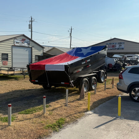 Trailer with a Texas flag design parked in front of a building with a car nearby.